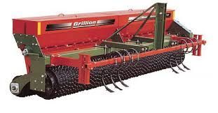 a red and green tractor with a roller attached to it .