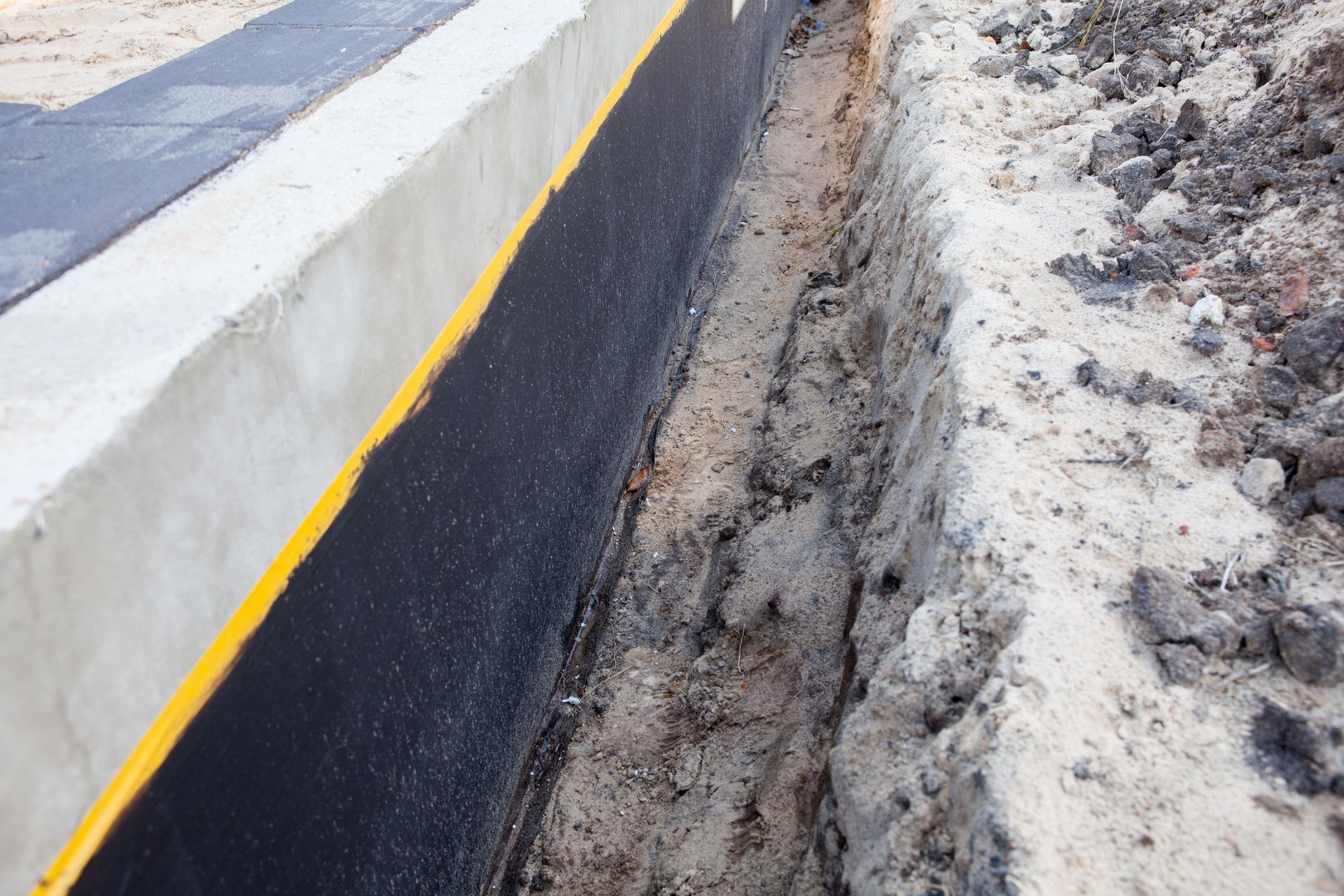 Un système de drainage est en cours d'installation sur un mur en béton.
