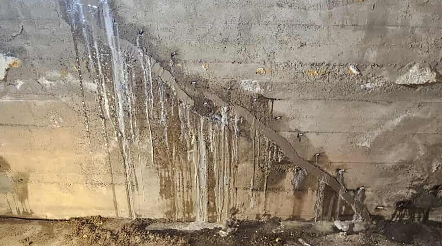 Un gros plan d'un mur en béton avec de l'eau qui en sort.