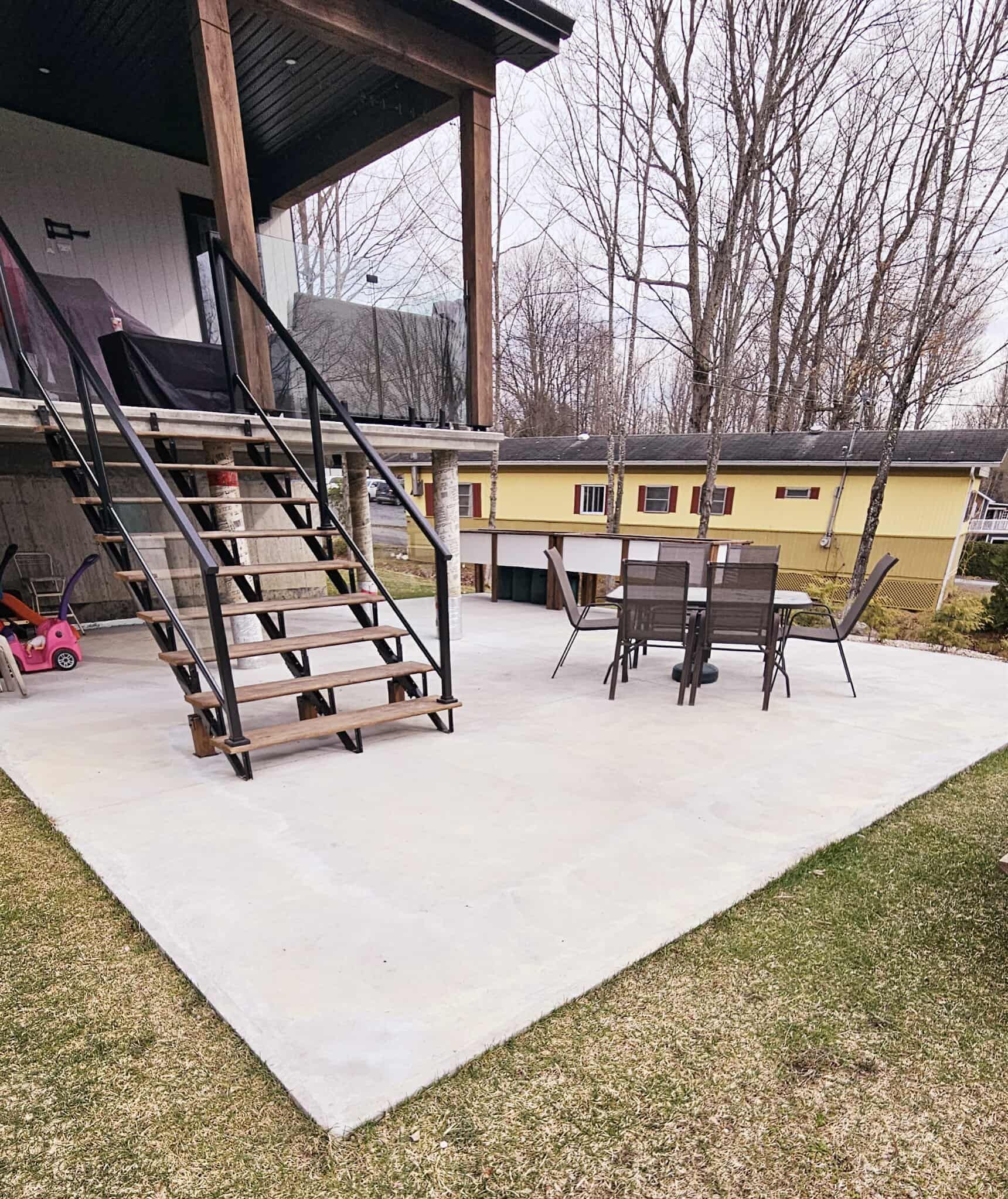 Un patio avec des escaliers menant à un porche et une table et des chaises.