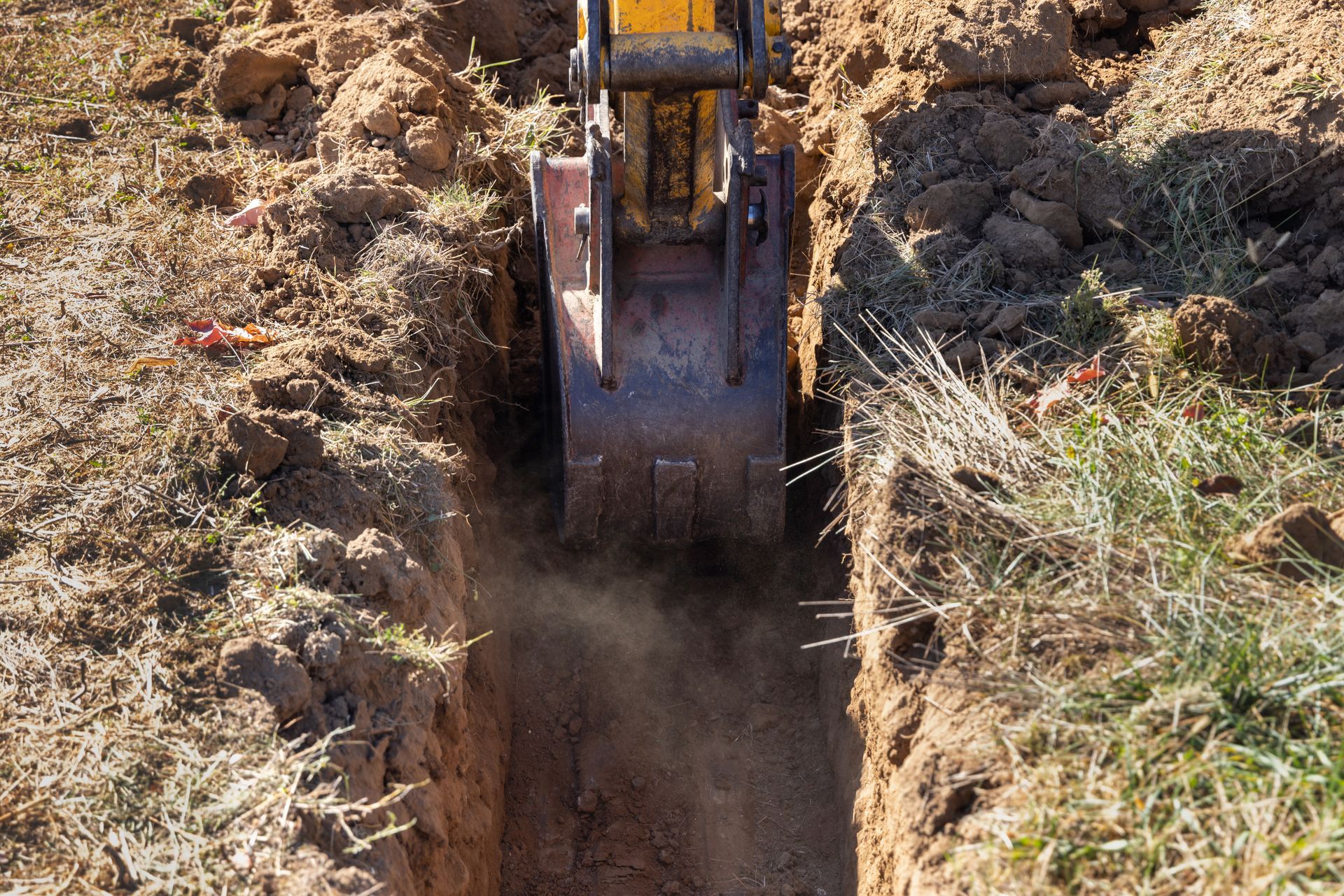Une excavatrice jaune creuse un trou dans le sol.