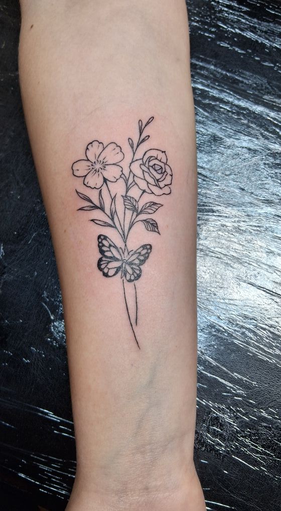 Tattoo of a floral bouquet with a butterfly on a forearm. Black line art.