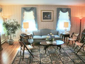 A living room with a couch , chairs , tables and a rug.