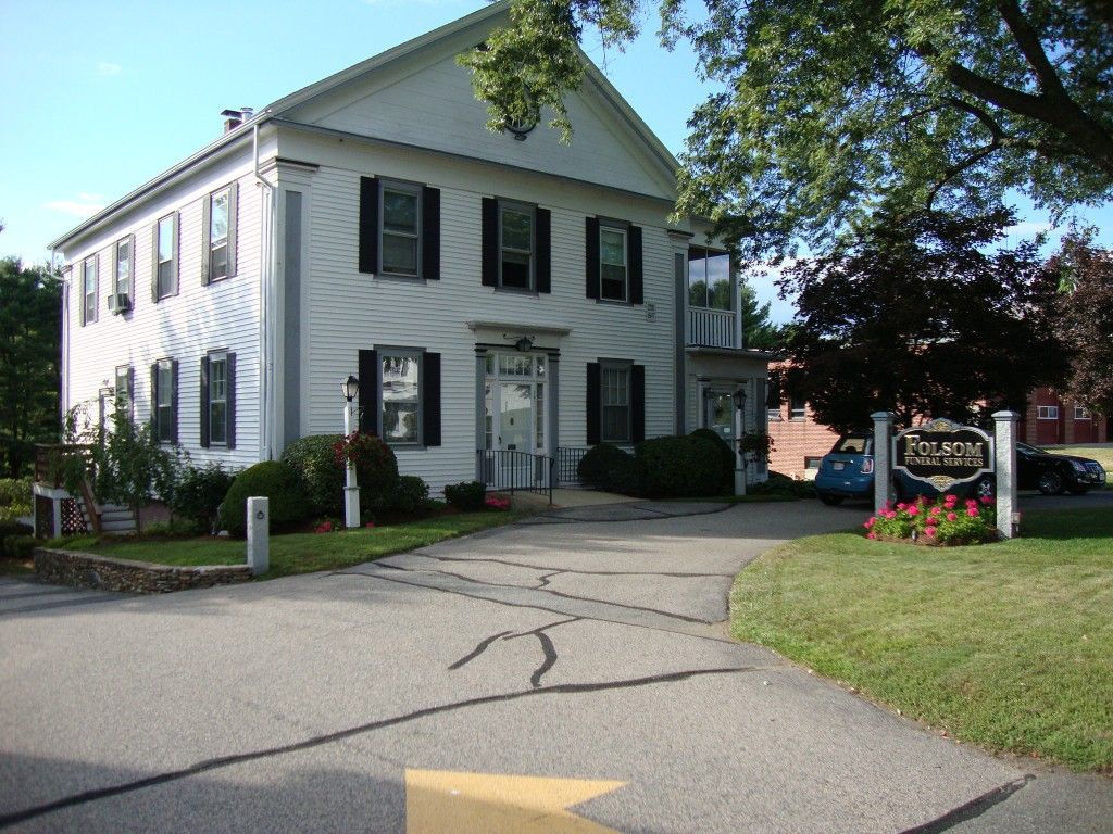 A large white house sits on the corner of a street