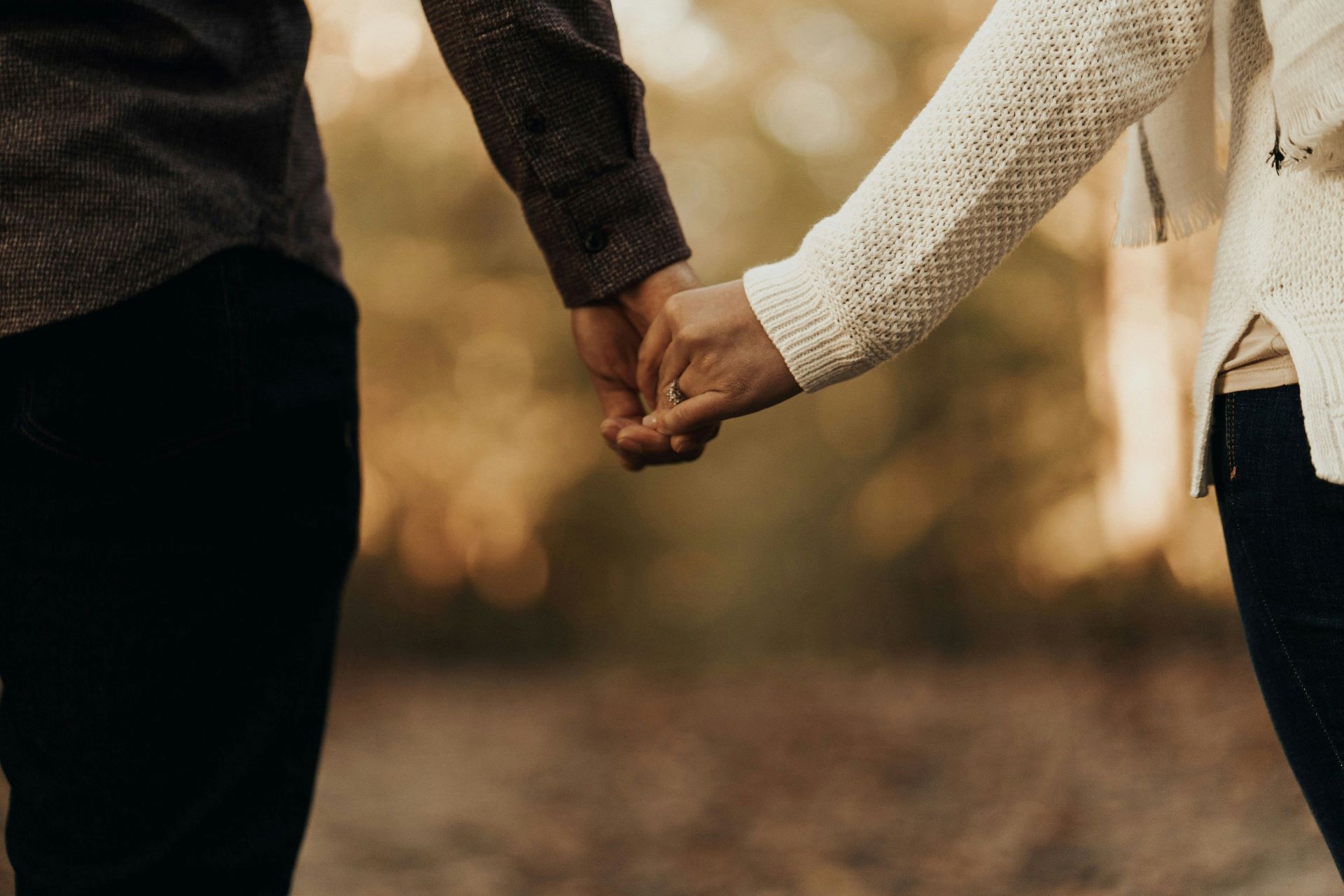 A man and a woman are holding hands in the woods.