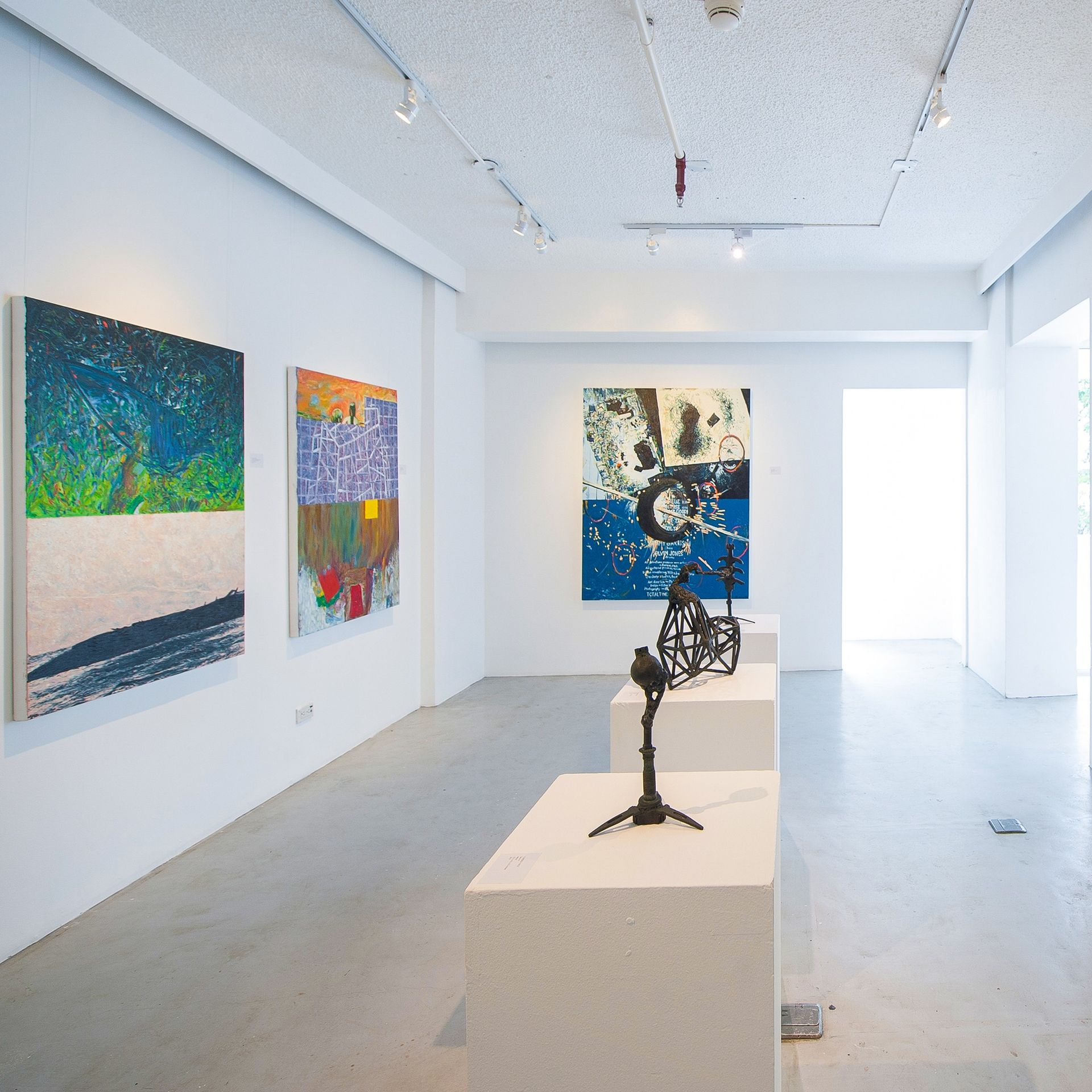 Bright white art gallery with colorful abstract paintings and sculptures on pedestals