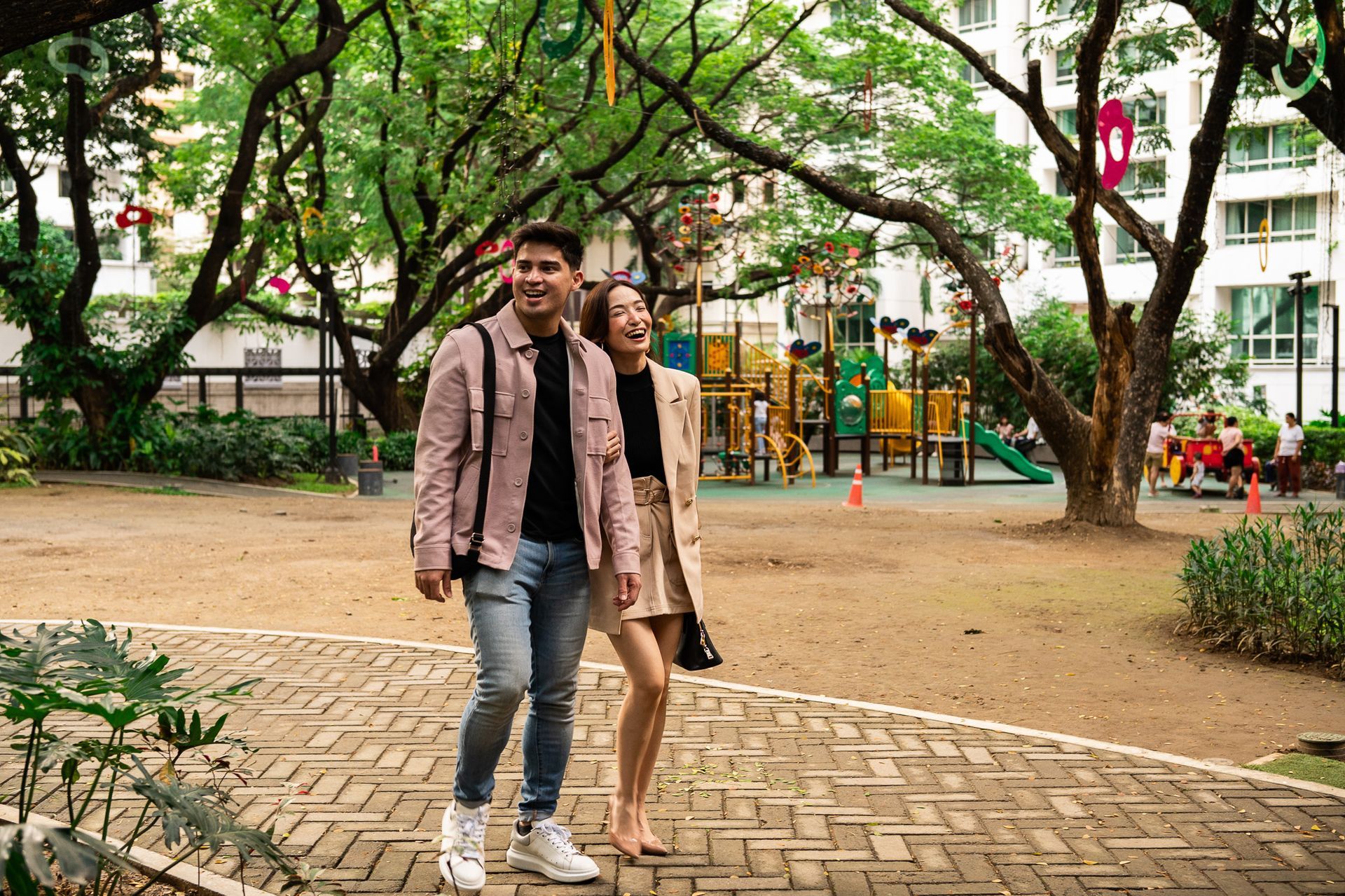 Happy couple walking through tree-lined park at Picasso Boutique Residences