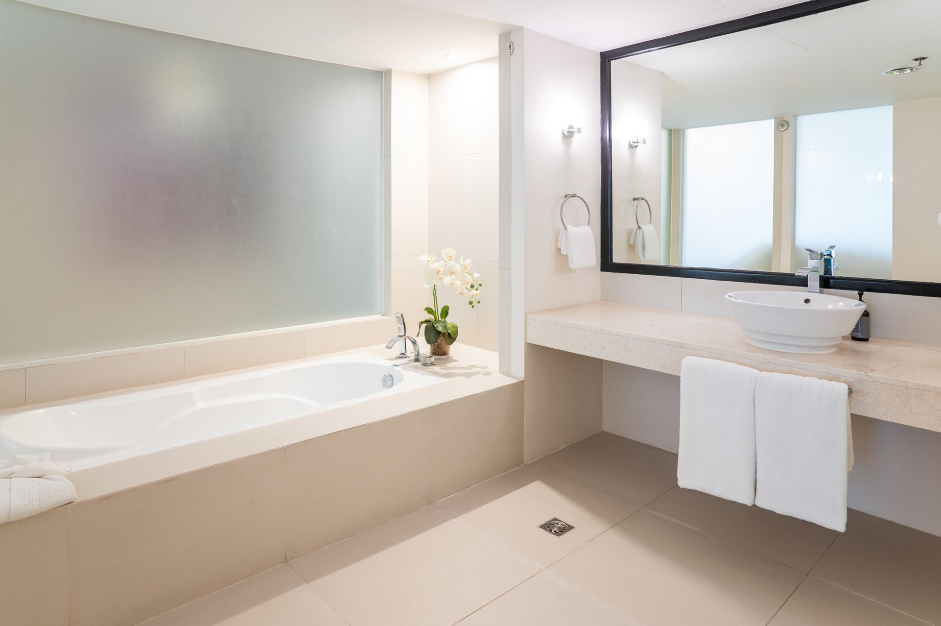 A bathroom with a tub sink and mirror