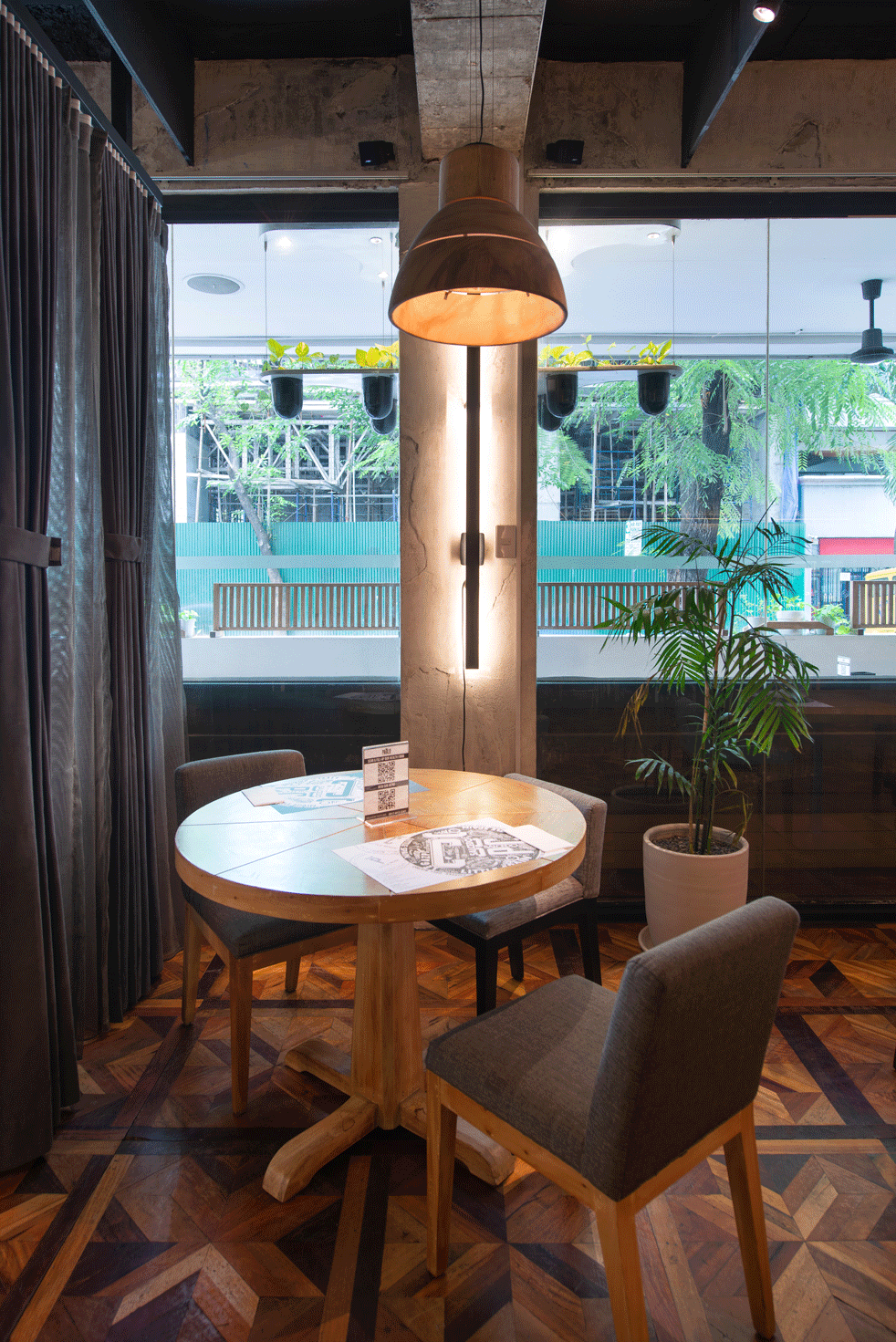 Cozy cafe corner with round table, two chairs, warm pendant light, and large window view outside