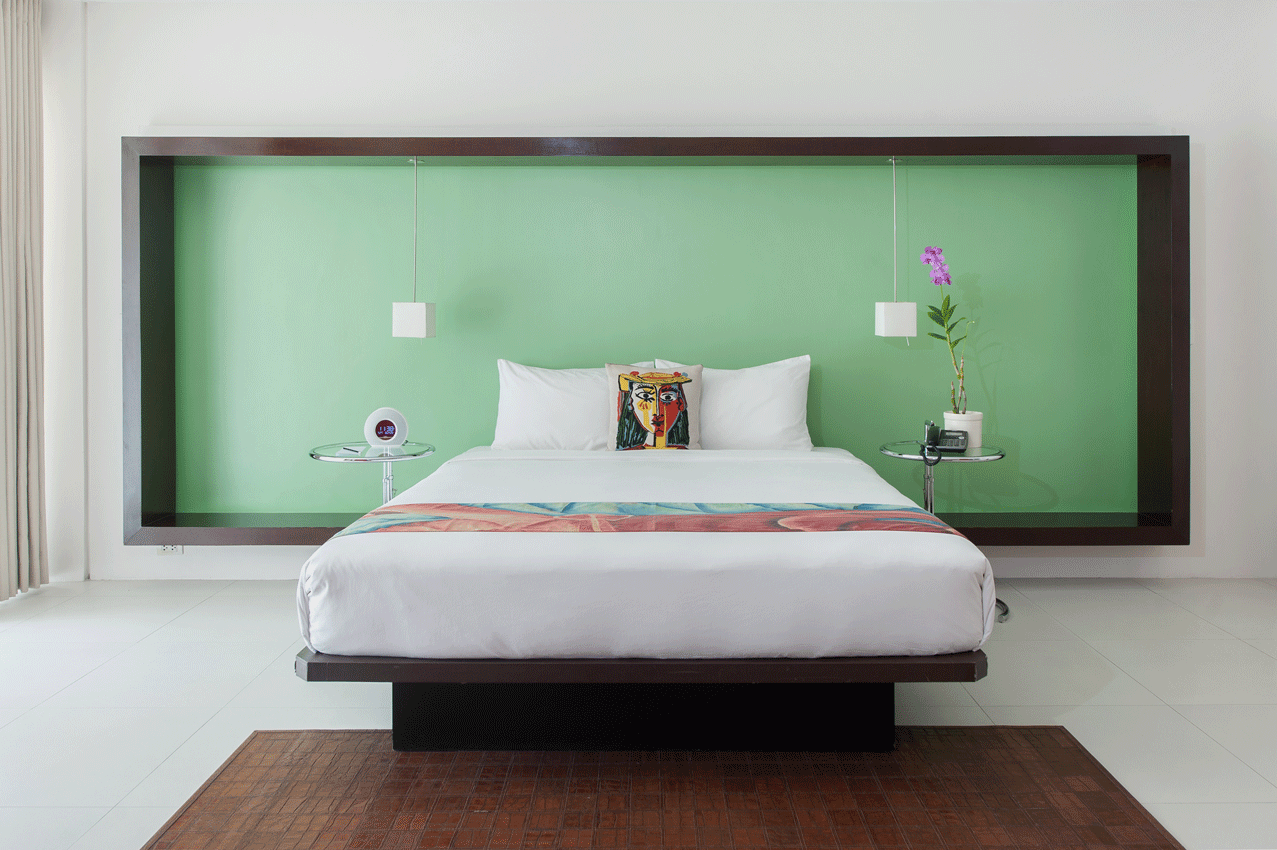 Modern bedroom with a bed centered against a green wall and a dark wood frame.