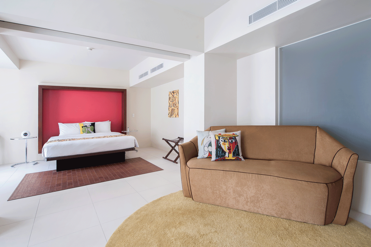 Spacious bedroom with wooden flooring and red accent wall in boutique serviced residences.