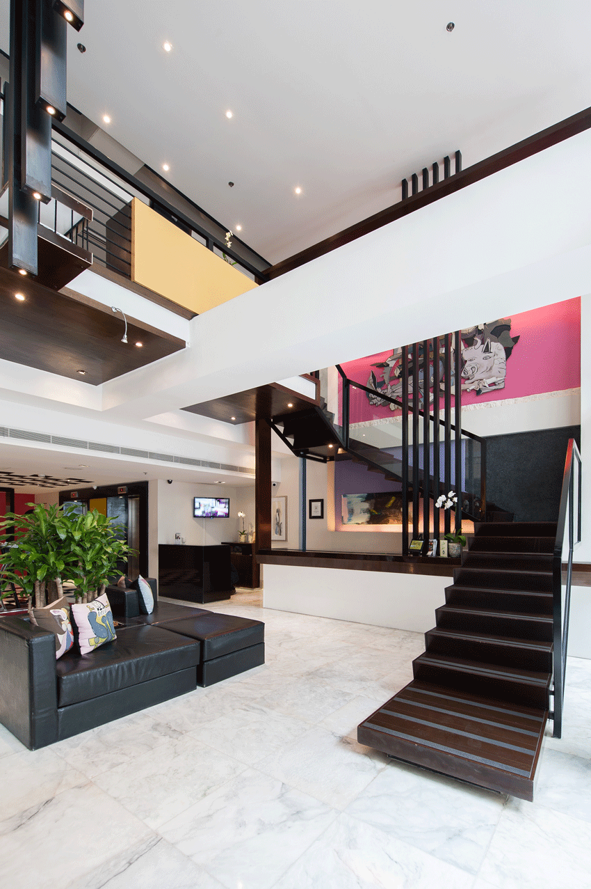 Modern hotel lobby with a black staircase and leather seating. Pink and black wall art.