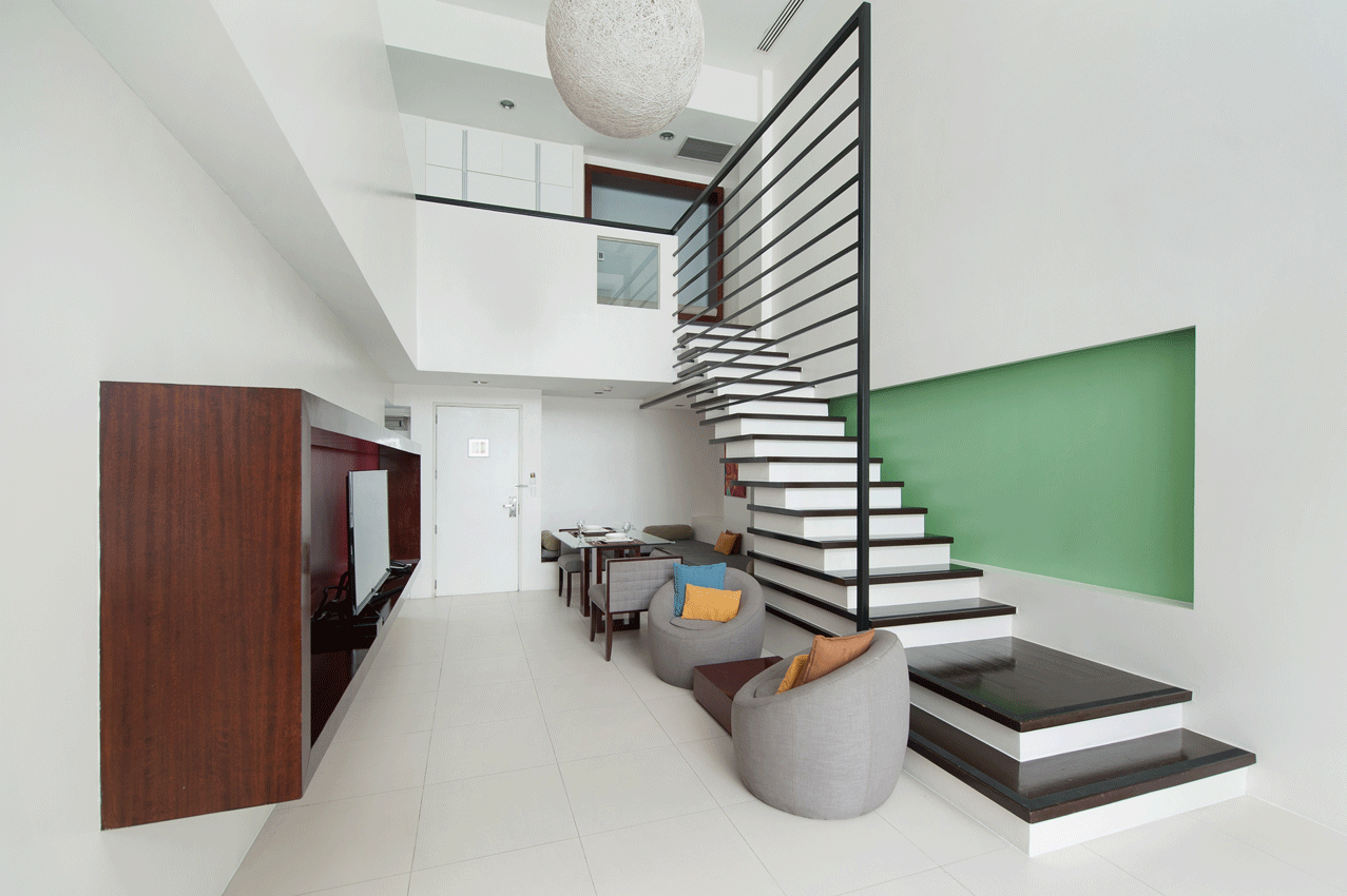 Modern loft with green accent wall and staircase in boutique serviced residences Makati.