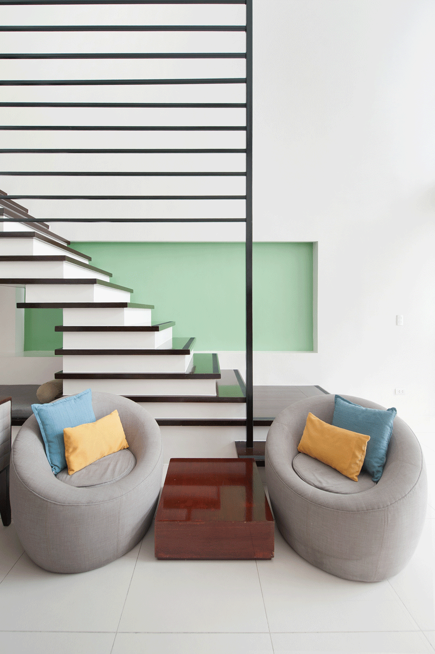 Modern living area with gray round chairs and open staircase at The Picasso