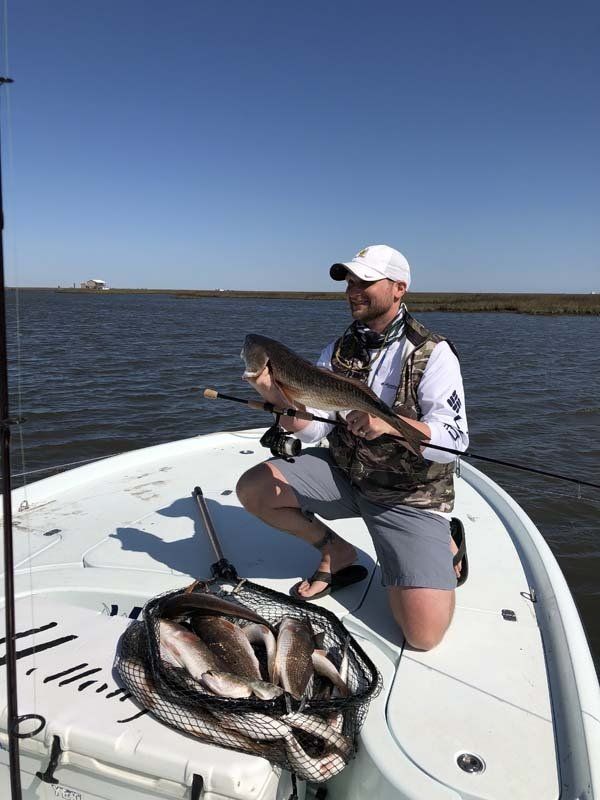 A man is kneeling on a boat holding a fish.