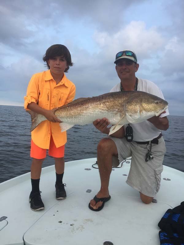 A man and a boy holding a large fish on a boat