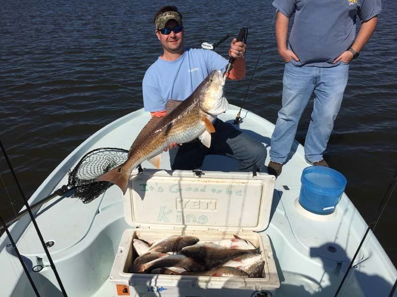 Two men are standing on a boat holding a large fish