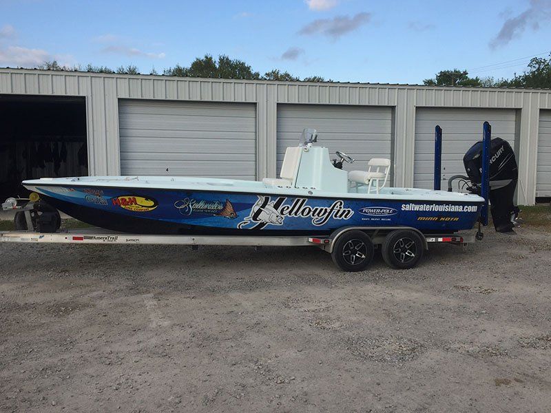 A boat is parked in front of a garage with the word hellafly on it