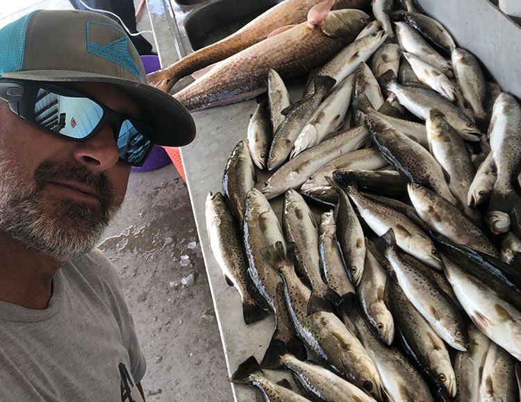 A man is standing in front of a pile of fish.