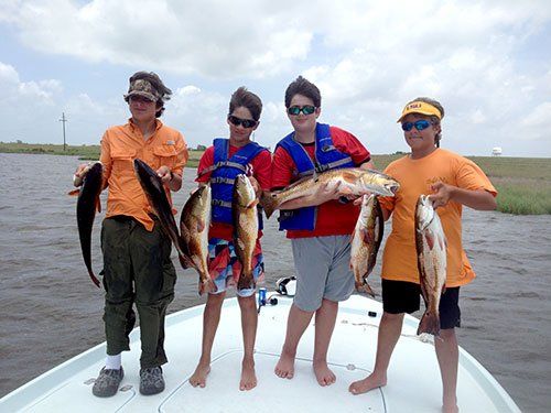 A group of people standing on a boat holding fish