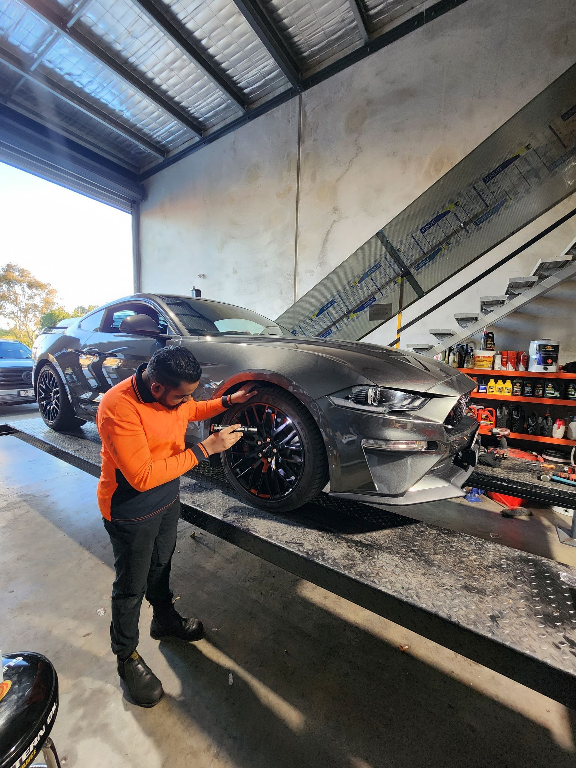 Man in Orange Shirt Works on a Gray Ford Mustang Inside a Shop — QA Oxley in Seventeen Mile Rocks, QLD