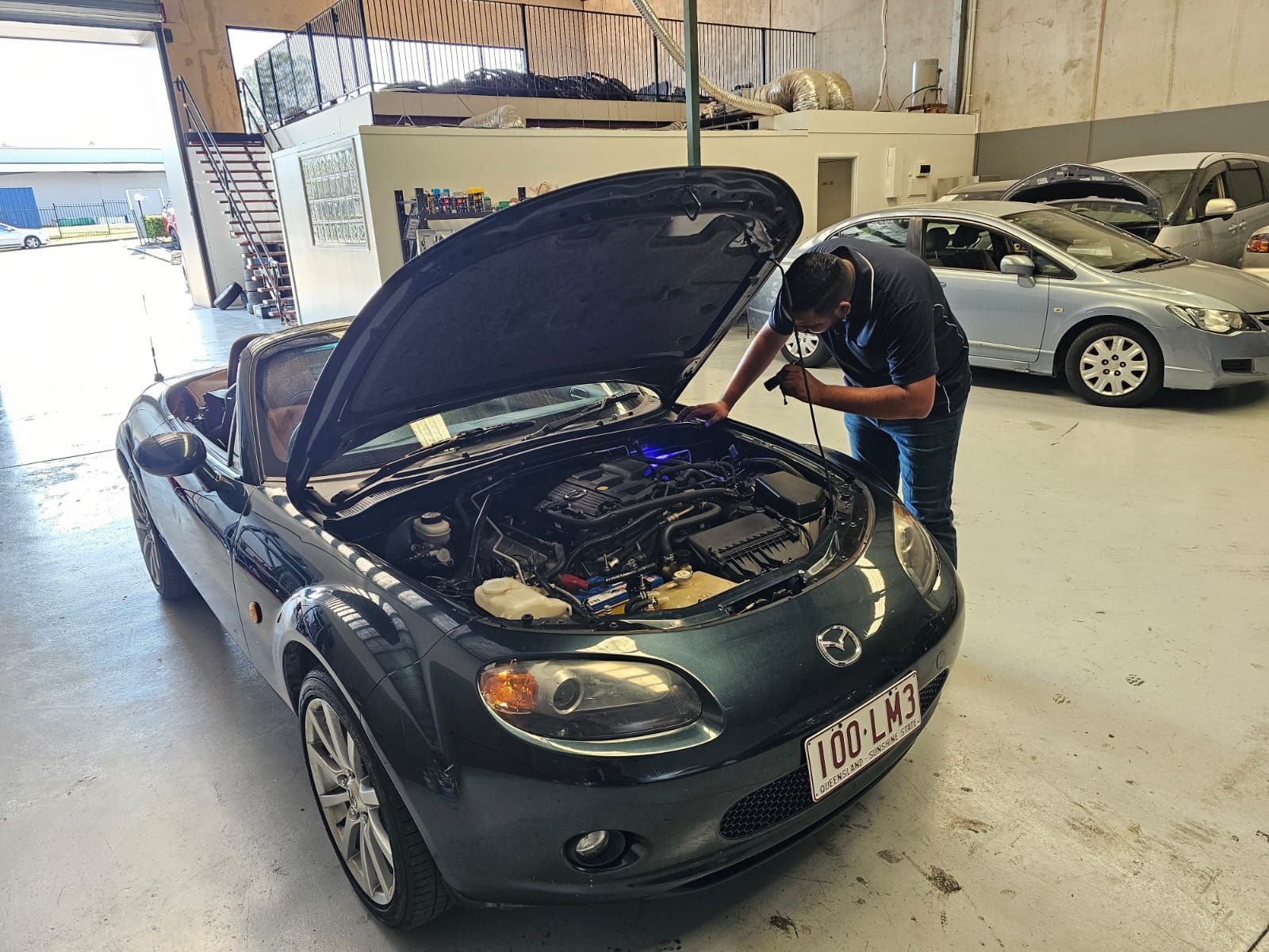 Mechanic Inspecting the Engine of a Green Mazda Miata in a Garage — QA Oxley in Seventeen Mile Rocks, QLD