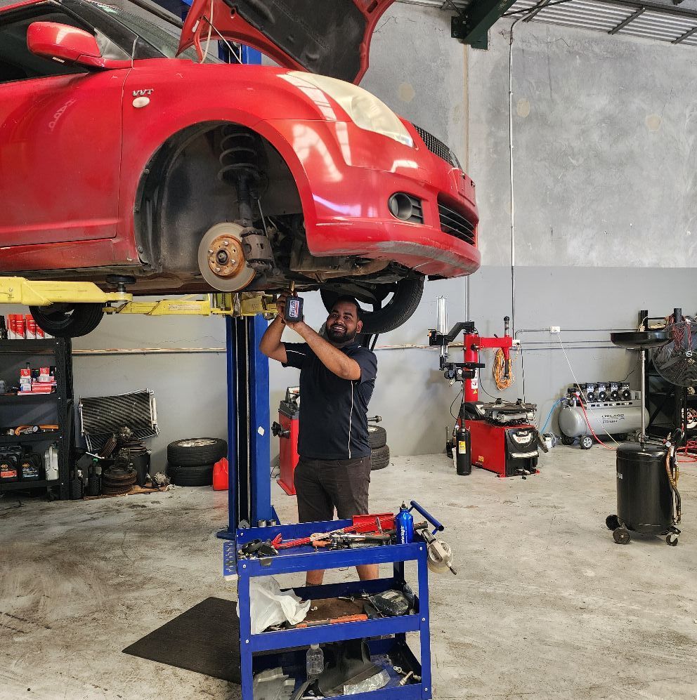 Mechanic Working Under a Red Car Raised on a Lift in a Garage — QA Oxley in Seventeen Mile Rocks, QLD