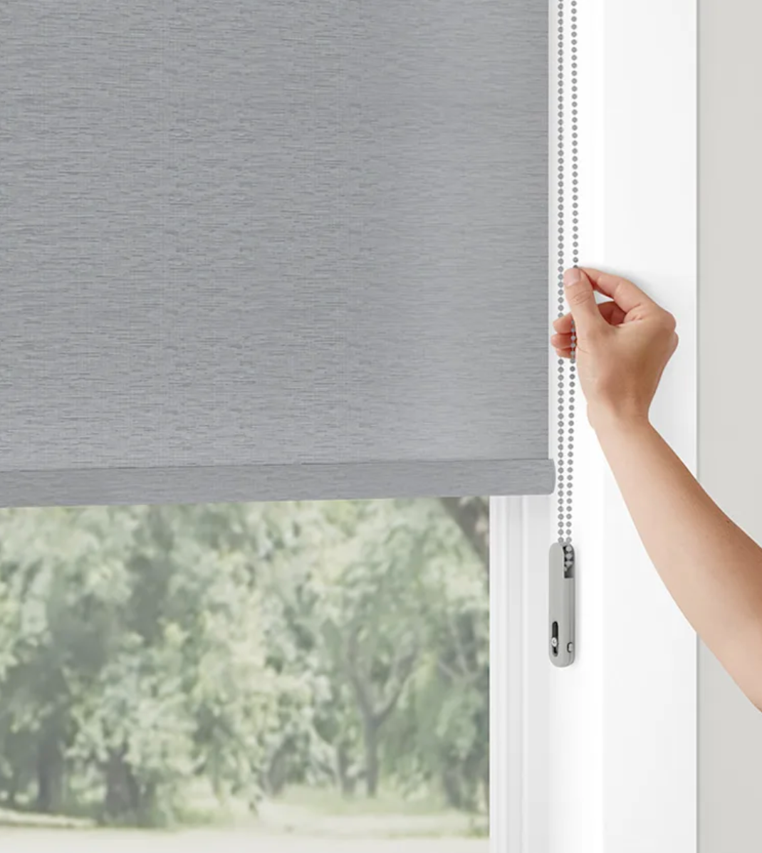 A person is adjusting a roller blind on a window.