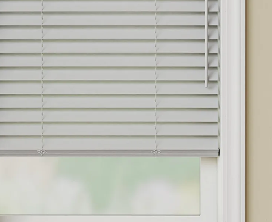 A close up of a white blind on a window.