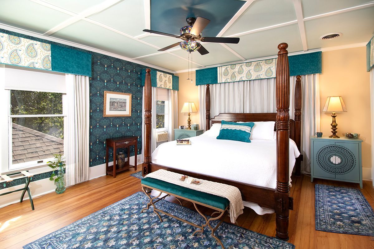 A bedroom with a four poster bed and a ceiling fan.