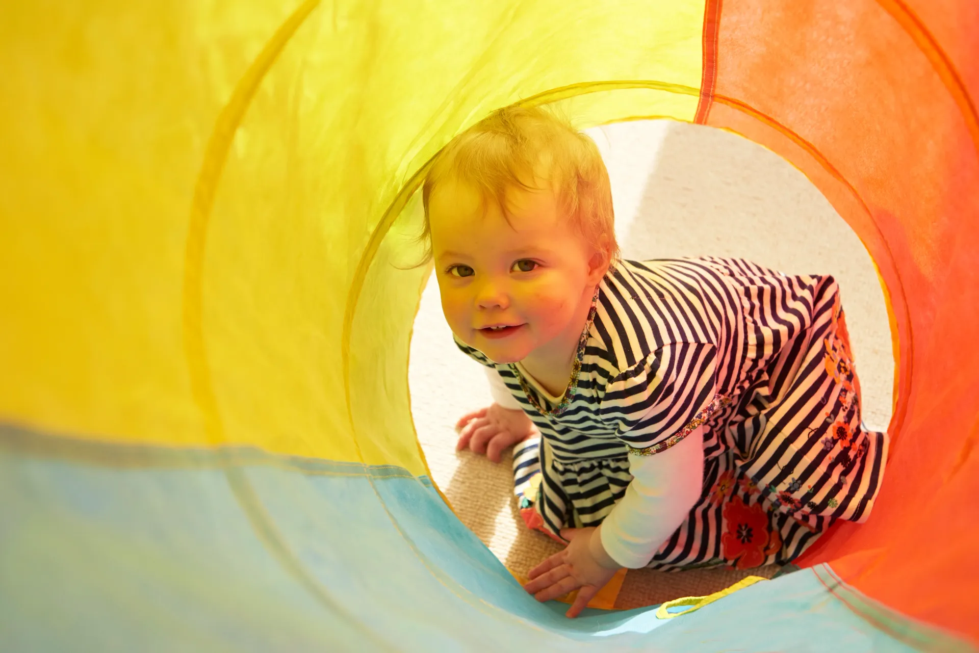 En baby kryper gjennom en fargerik tunnel.