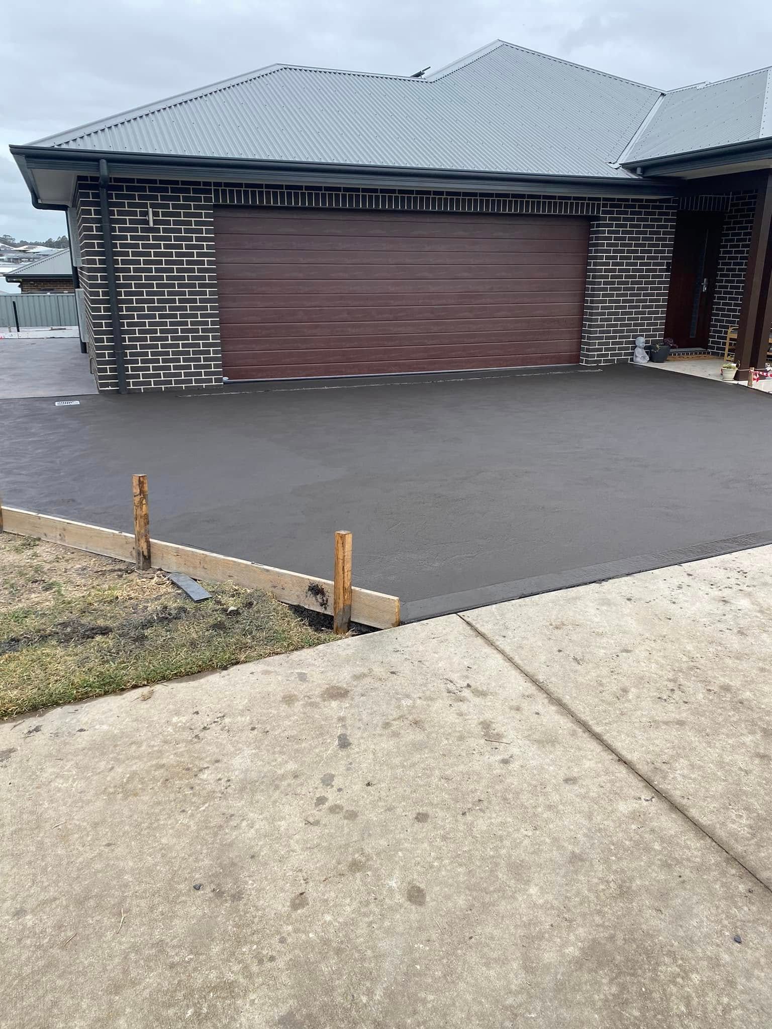 Suburban House With Garage Door And Freshly Paved Driveway — BJ's Concreting in North Nowra, NSW