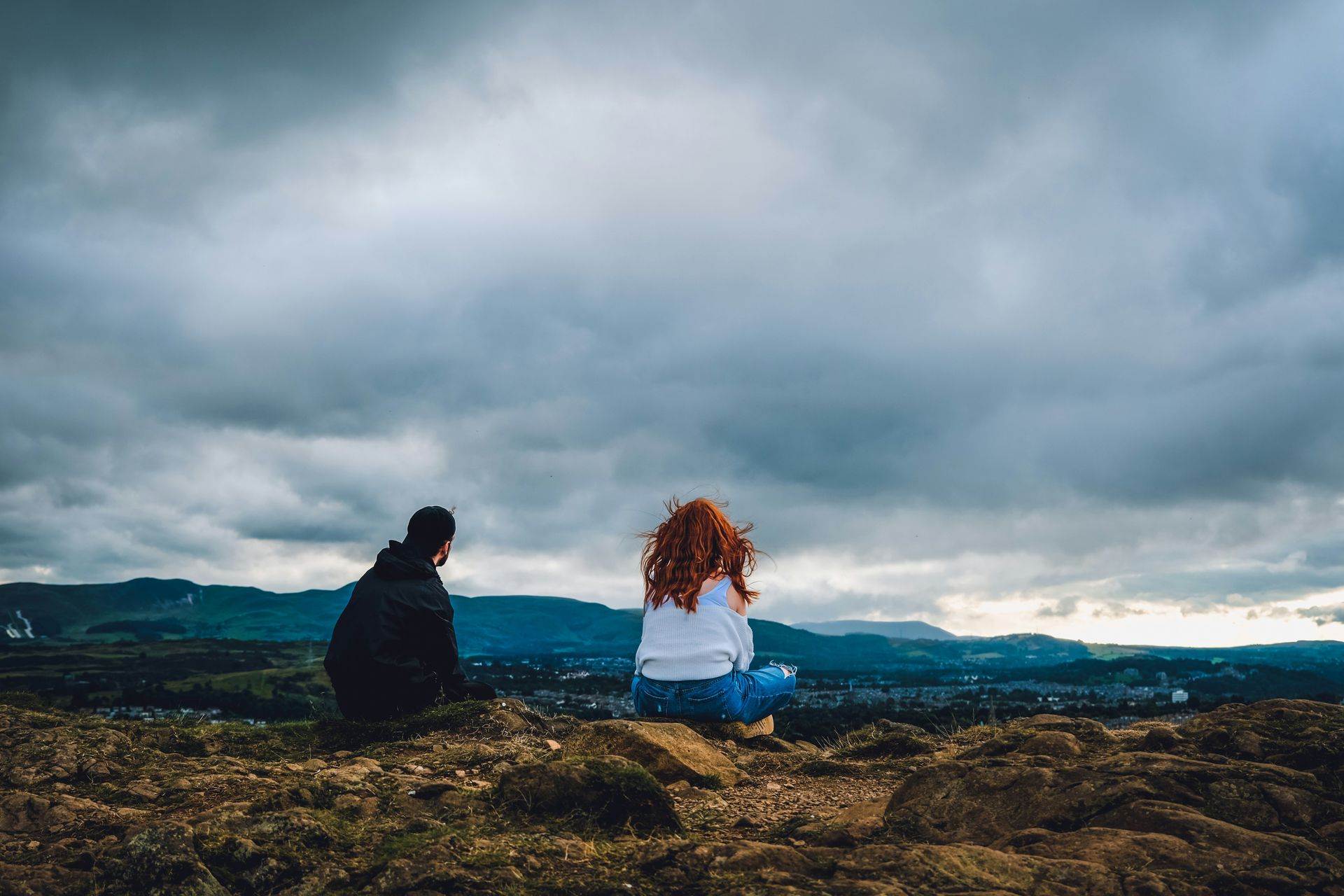 Man en vrouw zitten een beetje uit elkaar op een klif