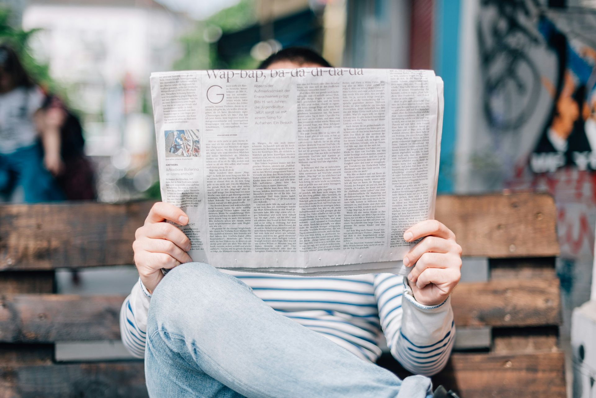 Persoon houdt een grote krant voor diens gezicht