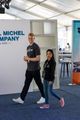 A man and a woman are walking in front of a sign that says michel company.