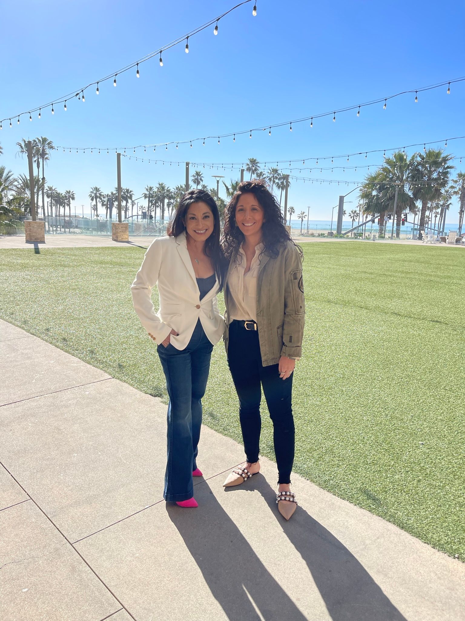 Two women are standing next to each other on a sidewalk.