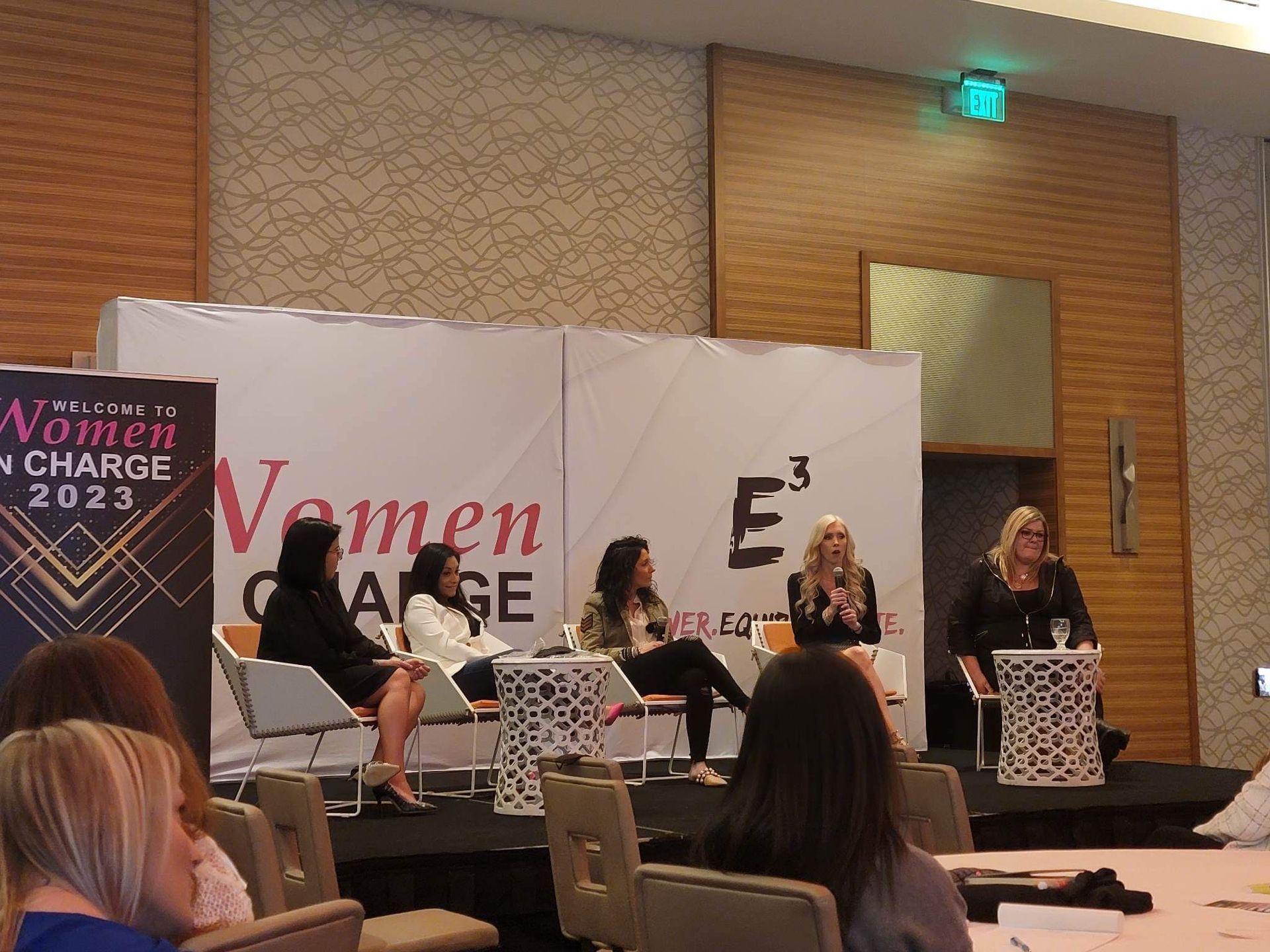 A group of women are sitting at a table in front of a sign that says women change 2023