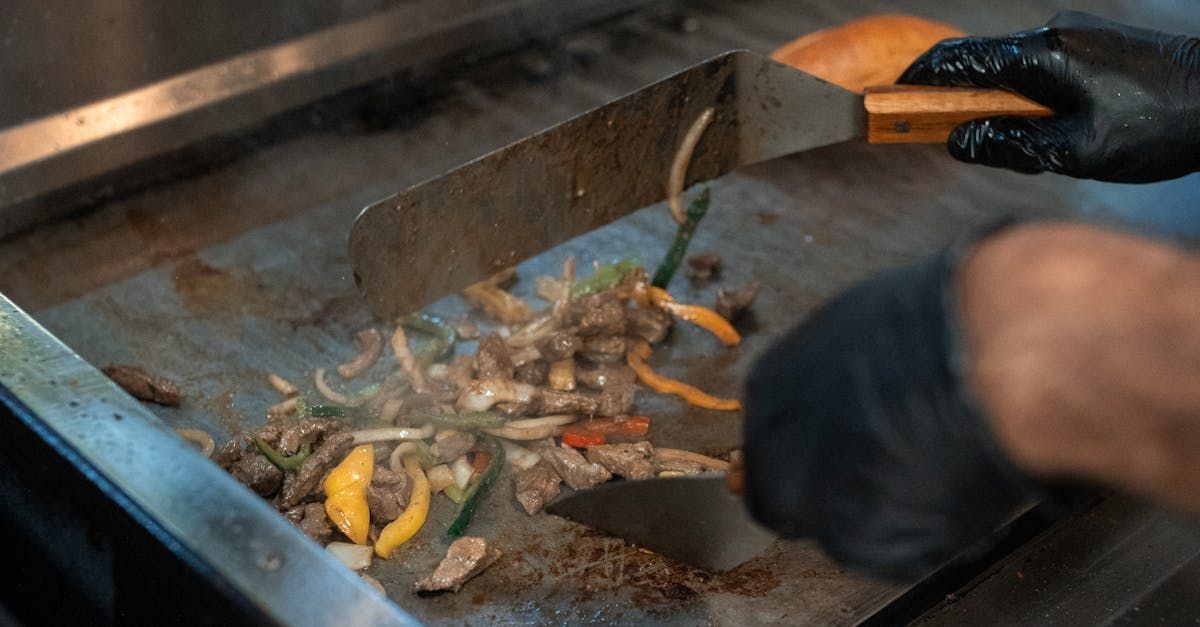 A person is cooking food on a grill with a spatula.