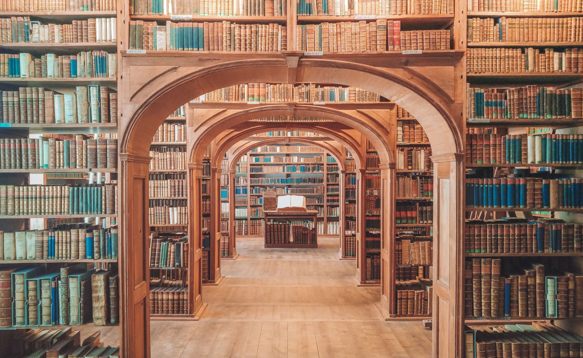 A large book under several old wooden arches in a well-stocked library