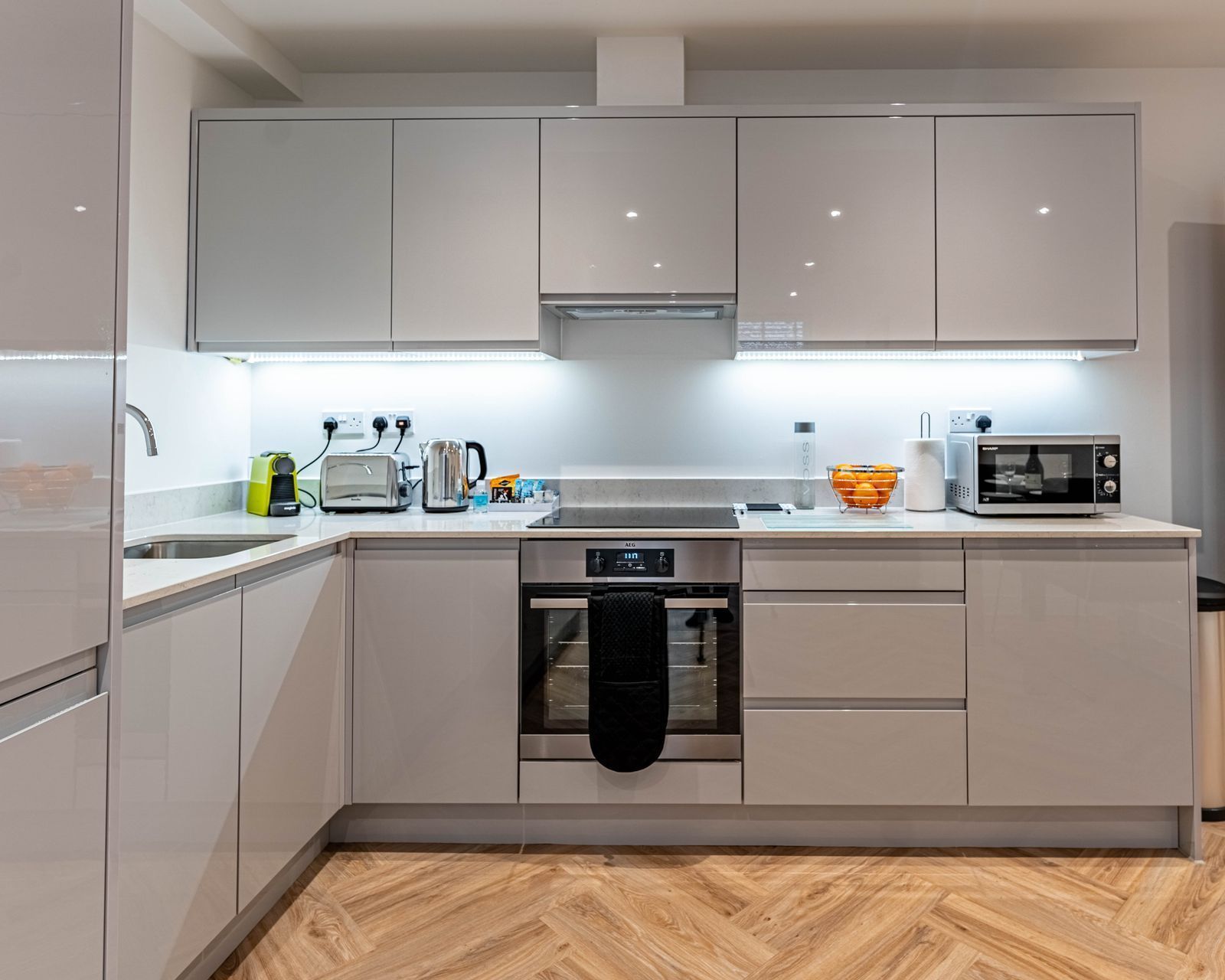 Modern kitchen with white cabinets, built-in appliances, countertop appliances, and a window.