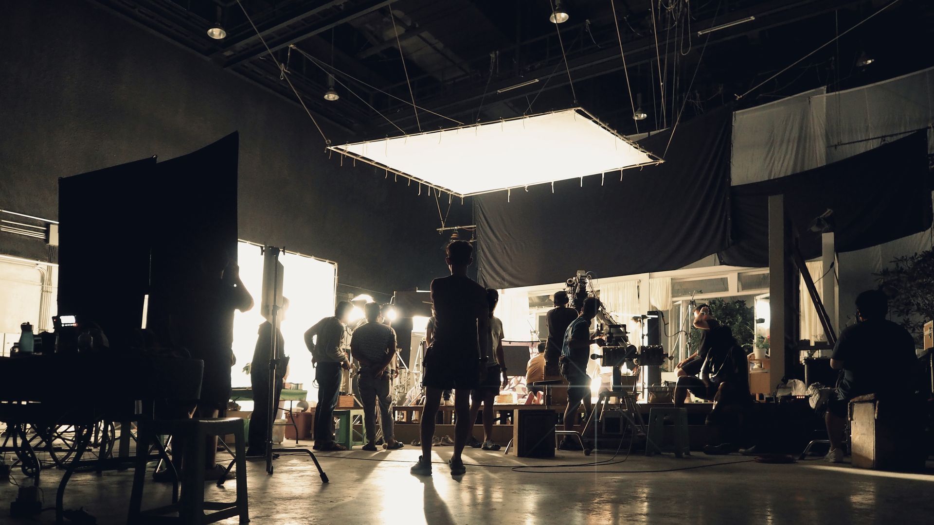 A professional film production set with crew members operating cameras and adjusting lighting in a controlled studio environment.