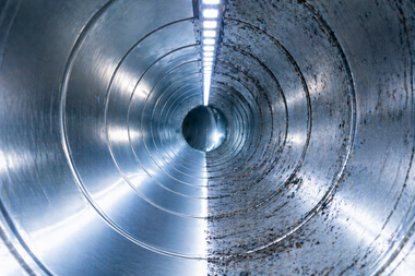 Inside a metal pipe or tunnel with a reflective, blue-gray interior and concentric rings