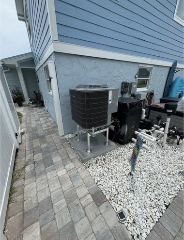 Side yard with HVAC unit, brick pavers, and blue house siding beside a white gravel bed.
