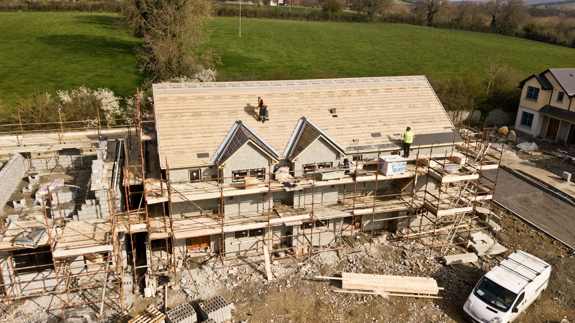 Une vue aérienne d'une maison en construction avec une camionnette garée devant.