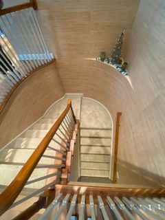 Top-down view of a curved staircase with wooden banisters and white walls