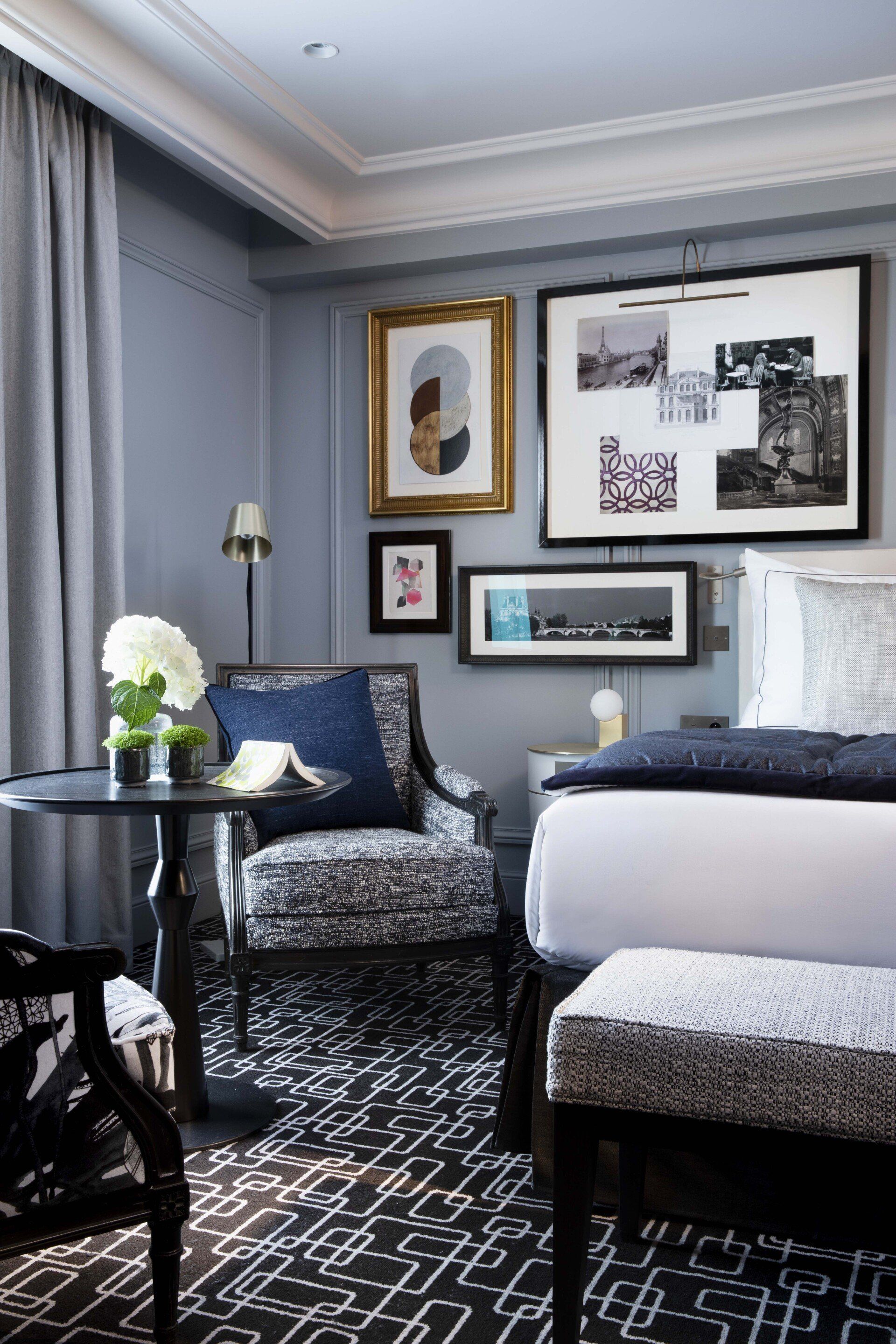 Une chambre d'hôtel avec un lit, une chaise, une table et des tableaux sur le mur.