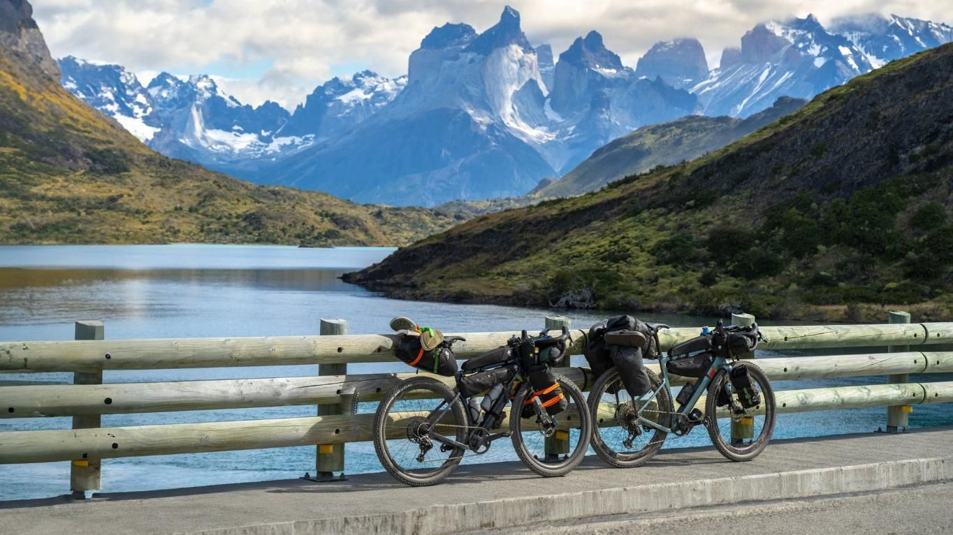Two Bicycles Are Parked On A Bridge Over A Lake With Mountains In The Background — Trinity Cycle Works In Cairns City, QLD