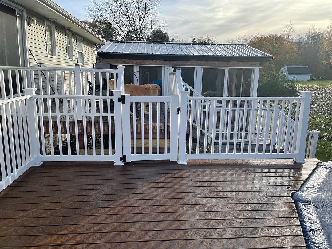 A wooden deck with a white railing and a gate.