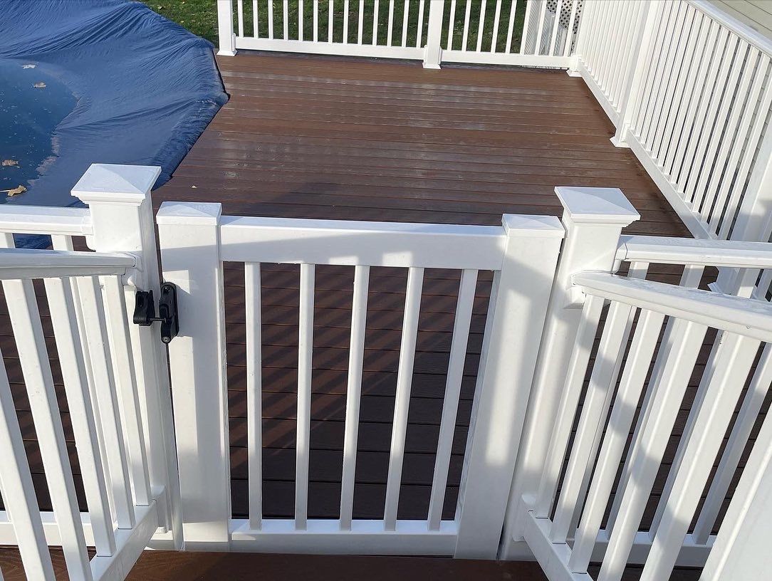 White gate with brown deck and white railing, near a pool.