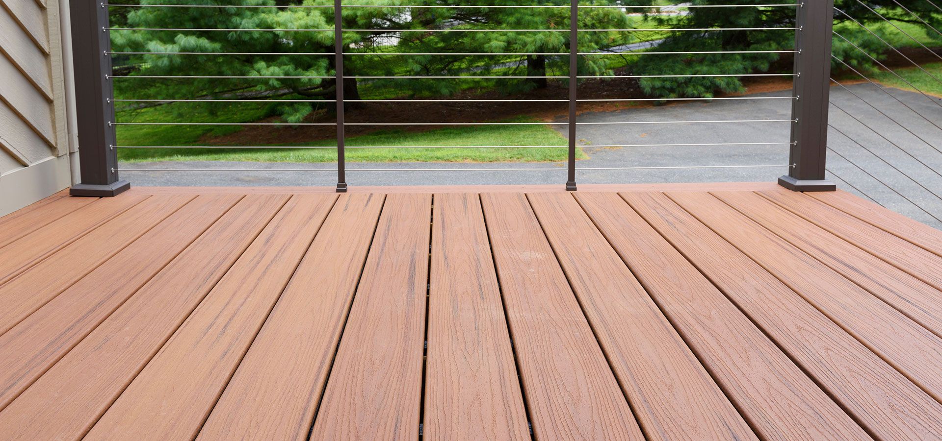 A wooden deck with a metal railing and trees in the background.